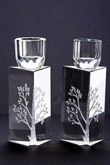Pair of triangular clear crystal candlesticks with etched tree of life and faceted crystal cups on dark backdrop