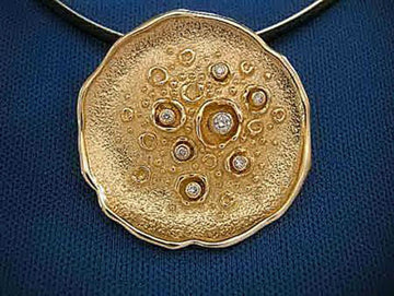 Textured gold disk pendant with bezel-set diamonds among raised circles, on a dark cord