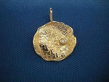 Round hammered-texture gold pendant with a single small diamond, hanging from a slim bale