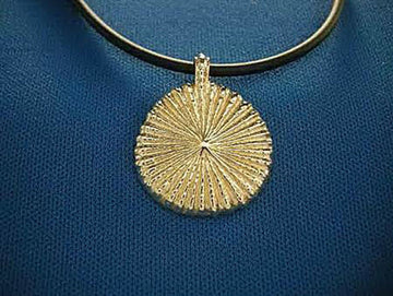 Round gold sunburst pendant with fine radiating ridges, strung on a black cord