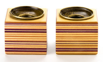 Pair of striped layered-wood cube candle holders with antiqued brass cups on white