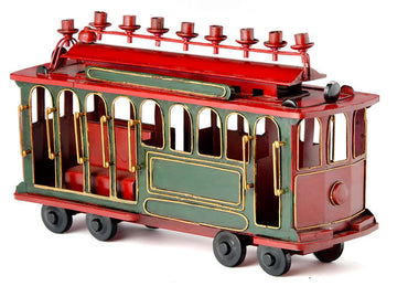 Red and green metal trolley car menorah with arched windows and red candle cups on the roof