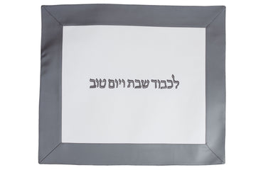 White vinyl challah cover framed in silver-grey with dark Hebrew lettering across the center