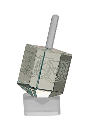Pale green etched glass dreidel tilted on a frosted stand, showing Hebrew letter faces