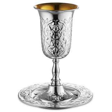 Tall stemmed silver-coated goblet embossed with flowers and vines, gold interior, on a floral plate