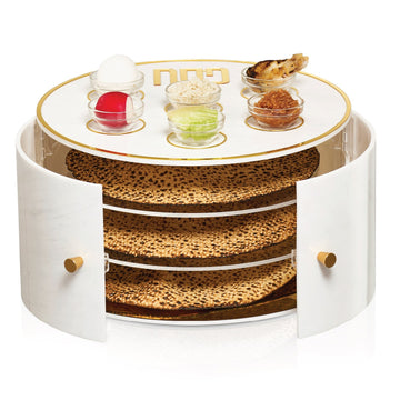 Three-tier white marble Kearah with doors open on stacked matzahs and simanim bowls on top