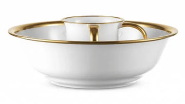 White acrylic washing cup with gold handles resting in a white bowl with a gold rim