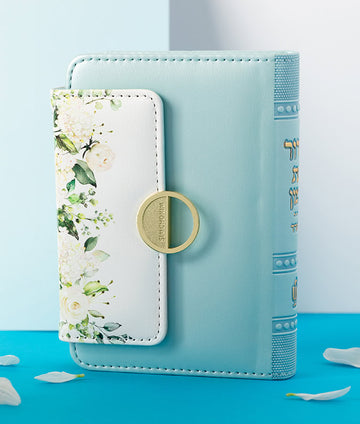 Simchonim Floral style pocket siddur in mint, shown on a table setting