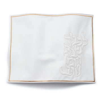 White faux leather challah cover with gold trim and embossed leaf design, flat lay