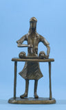 Bronze figure of a girl with long hair reading from an open Torah scroll at a table