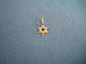 Tiny 14K yellow gold Star of David charm with a round open center on dark fabric