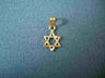 Small interwoven gold Star of David charm with faceted edges on blue-grey fabric