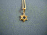 Mini high polish 14K gold Star of David pendant shown hanging on a gold chain