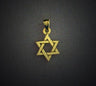 Petite interwoven 14K yellow gold Star of David pendant glowing against a dark background