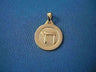 Round gold medallion with a raised Chai on a textured center and polished rim, on blue fabric