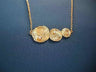 Three graduated textured gold discs in a row, each with a diamond, on a fine gold chain