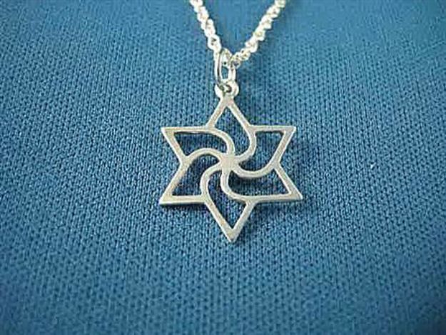 Silver Star of David with a swirling pinwheel center on a rope chain, on blue fabric