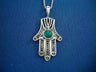 Silver filigree Hamsa with a round green Eilat stone and menorah cutout on blue fabric
