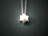 Small solid sterling silver Star of David with satin sheen strung on a fine link chain, dark background