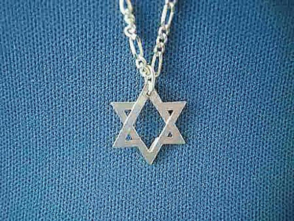 Small sterling silver two-piece Star of David on a figaro chain against blue knit fabric