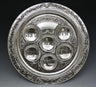 Round silver plated Seder plate with six Hebrew-engraved wells and a scrolling floral border