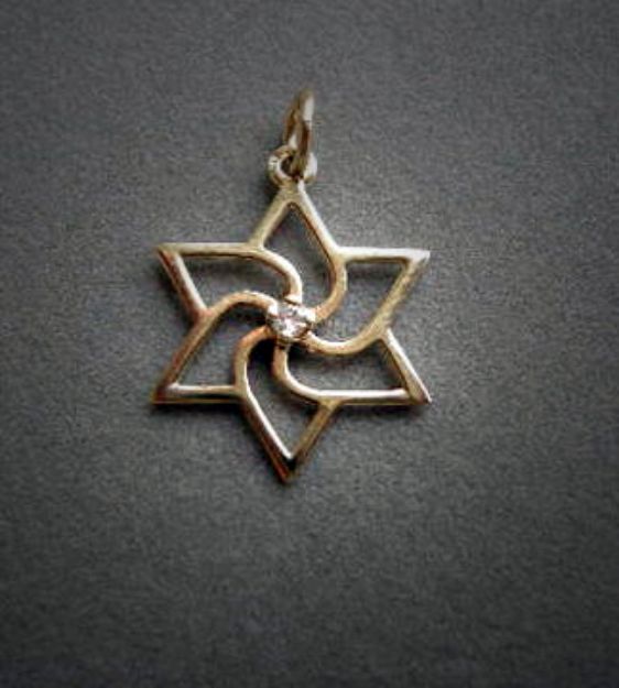 Yellow gold pinwheel Star of David pendant with a small center diamond on dark grey