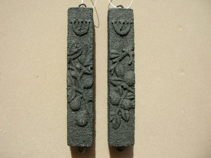 Black lava composite stone fig mezuzah case shown beside a second case, fruit relief and shin