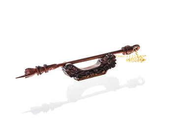 Dark sonokling ebony yad with carved pointing hand resting on an ornate carved stand, gold-tone chain at end