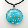 Round glass pendant with white blossoms on blue branches in Van Gogh style, on a black cord