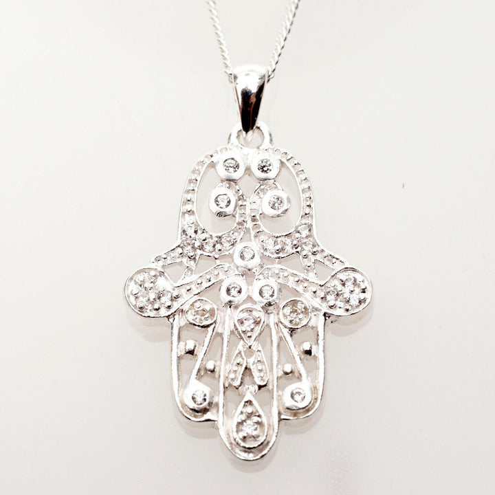 Openwork sterling Hamsa dotted with round CZs on a curb chain, pale background