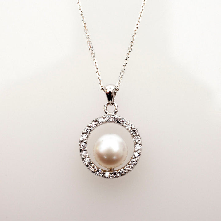 Freshwater button pearl inside a sterling silver ring of sparkling CZs on a fine link chain