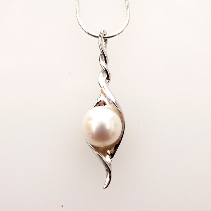 White button pearl cradled in a twisting sterling silver leaf pendant on a snake chain