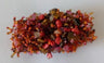 Stretch bracelet heaped with red, pink and brown stones and fringed in orange seed beads