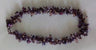 Purple amethyst cluster necklace laid in an oval loop on a pale grey background
