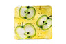 Square glass plate with halved green apples on a yellow background