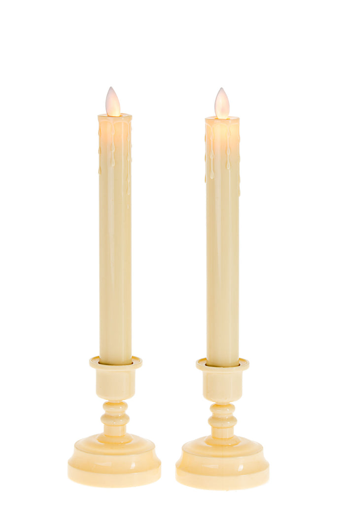 Two ivory LED taper candles with glowing flame tips standing in matching candleholder bases