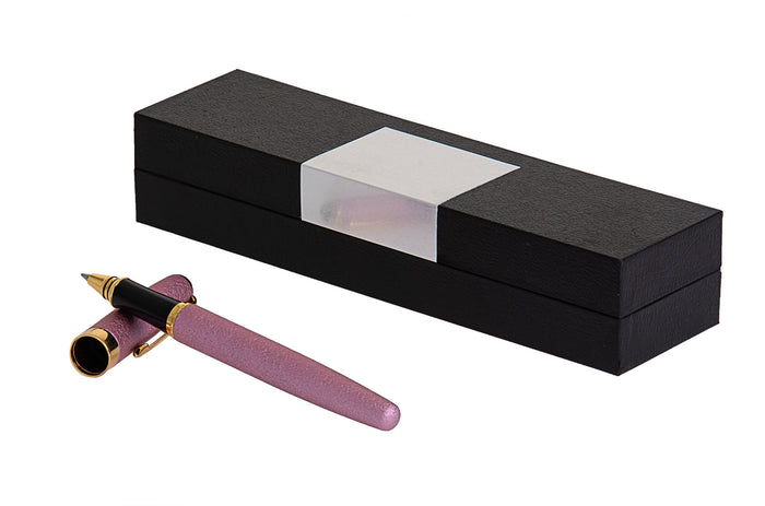 Pink pen with gold-tone trim lying beside a closed black gift box