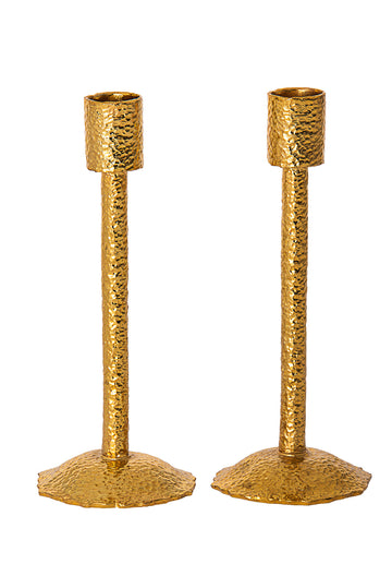 Two slim hammered gold metal candlesticks with cylindrical cups and wavy round bases