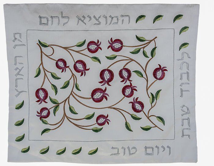 White challah cover with embroidered red pomegranates on a branch, Hebrew text and leaf border