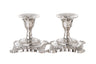 Two short polished stainless steel candlesticks with ornate scrolled square bases
