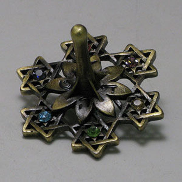 Antique brass-tone dreidel of six cut-out Stars of David with colored stones around a petal center