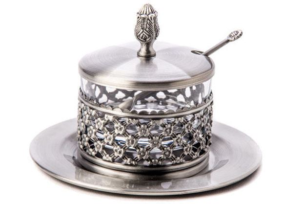 Silver plated lattice honey dish with a clear inner dish, finial lid and spoon on a round tray
