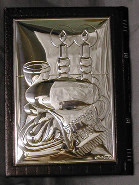 Black leather Zemiros with a polished sterling silver cover in relief of candles, challah and a Kiddush cup