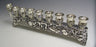 Low silver plated row menorah with nine cups, a raised end shamash and a relief-decorated base