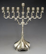 Compact silver plated menorah with looping scroll arms, raised center shamash and scalloped base