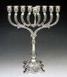 Silver plated menorah with engraved curved arms, a raised center shamash and an ornate footed base