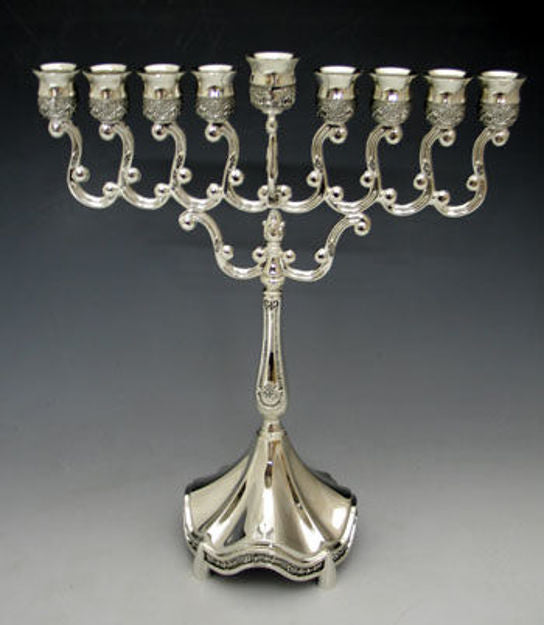 Silver plated menorah with looped scroll arms, raised center shamash and fluted flared base on grey