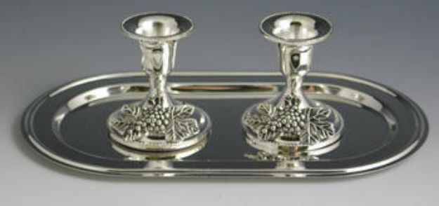 Two short silver plated candlesticks with grape cluster bases on an oval silver tray