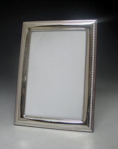 Small 4x6 sterling silver picture frame with polished border and beaded edge on a grey backdrop