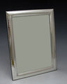 Upright 5x7 sterling silver picture frame with a textured inner border, angled against a dark background